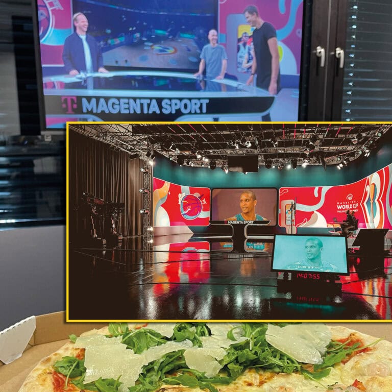 Ein Magenta Sport-Studio mit zwei Moderatoren und Gast. Bildschirm, technischen Geräte, und Pizza im Vordergrund.