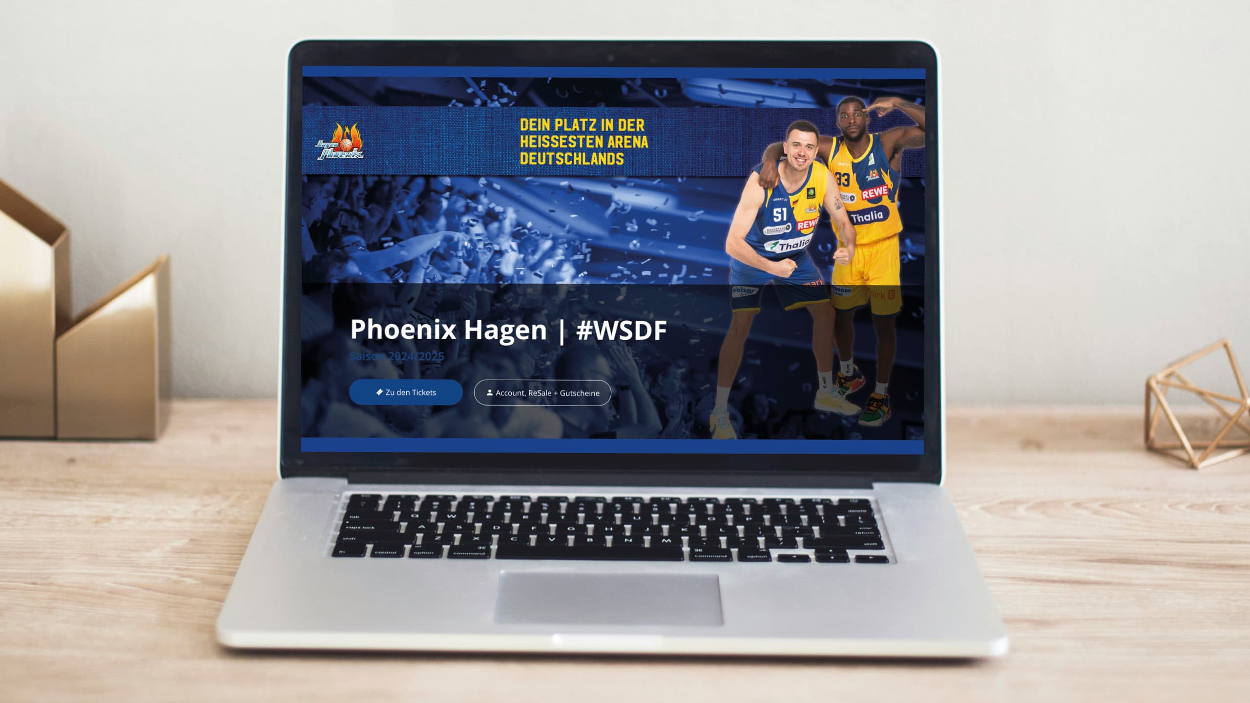 Laptop mit Webseite eines Basketballteams; zwei Spieler in blauen und gelben Trikots jubilieren.