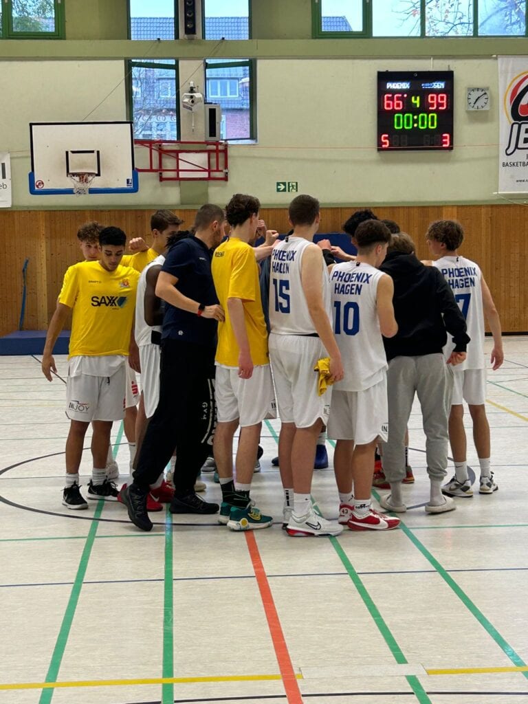 Basketball-Team in gelben und weißen Trikots umarmt sich freudig auf einem Spielfeld.