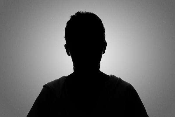 Ich kann die Person nicht identifizieren. Silhouette vor grauem Hintergrund, neutraler Ausdruck.