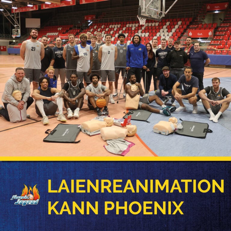 Gruppenfoto in Sporthalle; Basketballteam, teils in Uniform, mit Mannequins für Reanimationstraining.