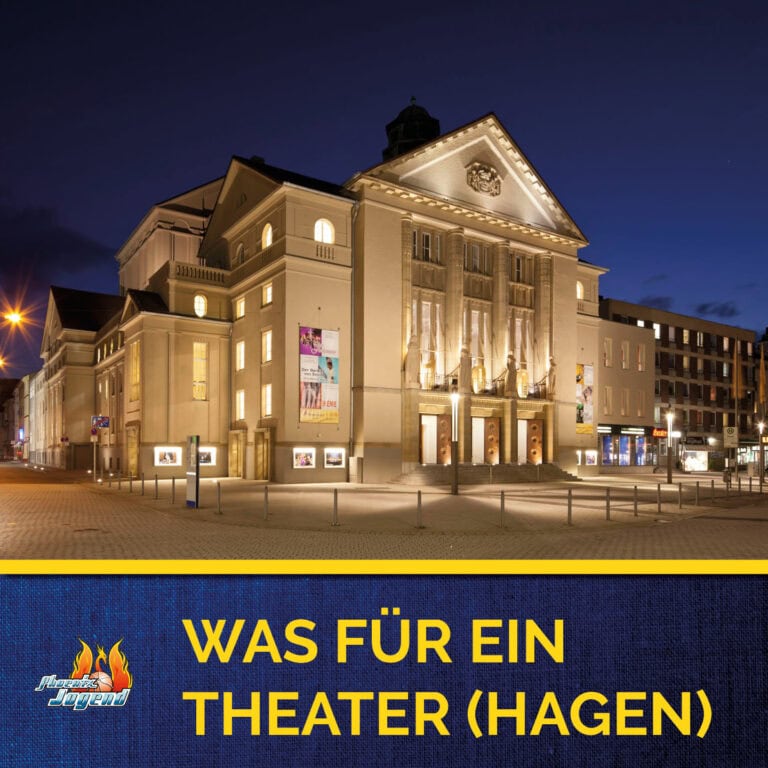 Das Theater Hagen bei Nacht, beleuchtet, mit Plakaten und einem klaren blauen Himmel im Hintergrund.