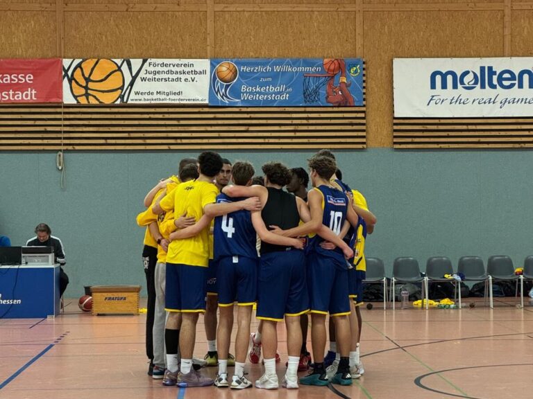 Eine Gruppe von Basketballspielern umarmt sich in einem Hallenspielfeld.