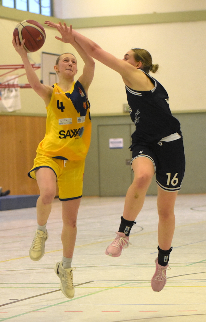 Eine Basketballspielerin im gelben Trikot wird von einer anderen im blauen Trikot verteidigt.