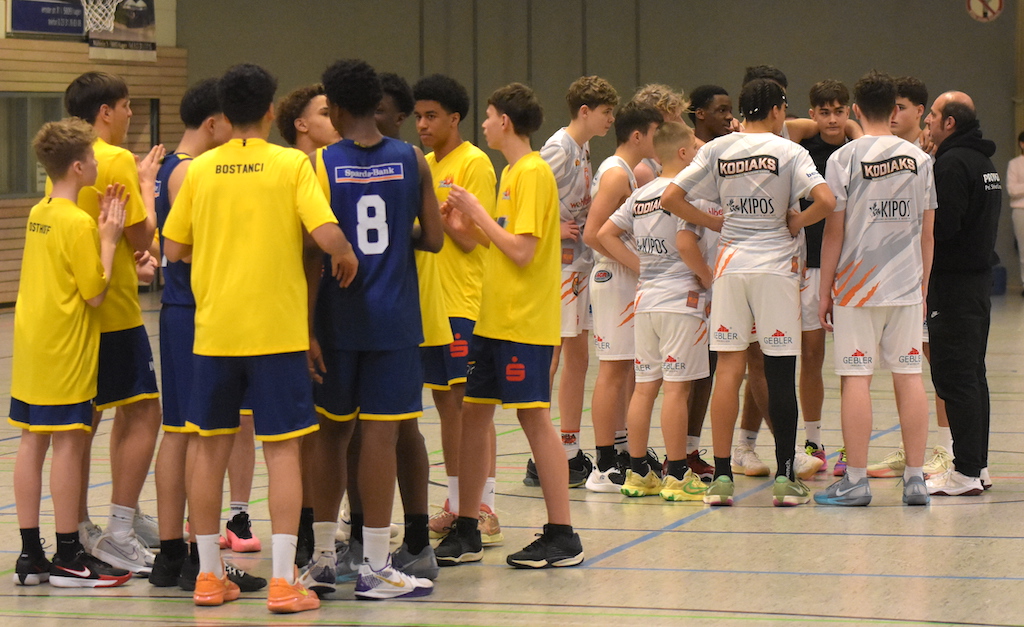 Jugendbasketballspieler in gelben und weißen Trikots stehen in zwei Gruppen, konzentrieren sich.