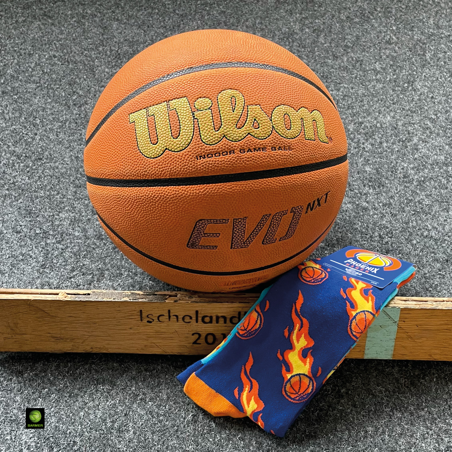 Ein Wilson-Basketball auf grauem Boden, daneben bunte Flammensocken.