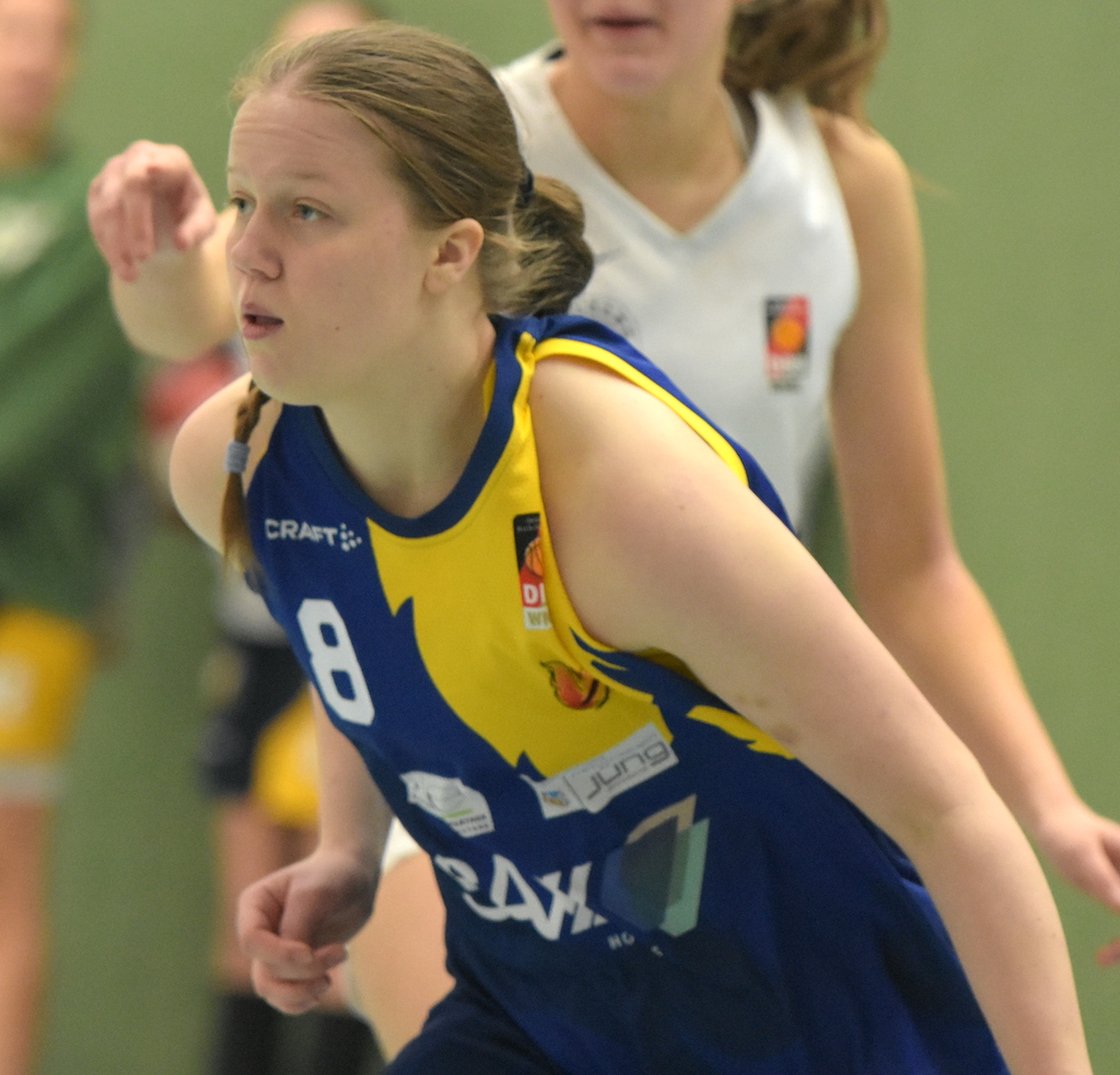 Frau spielt konzentriert Basketball in blau-gelbem Trikot mit der Nummer 8.